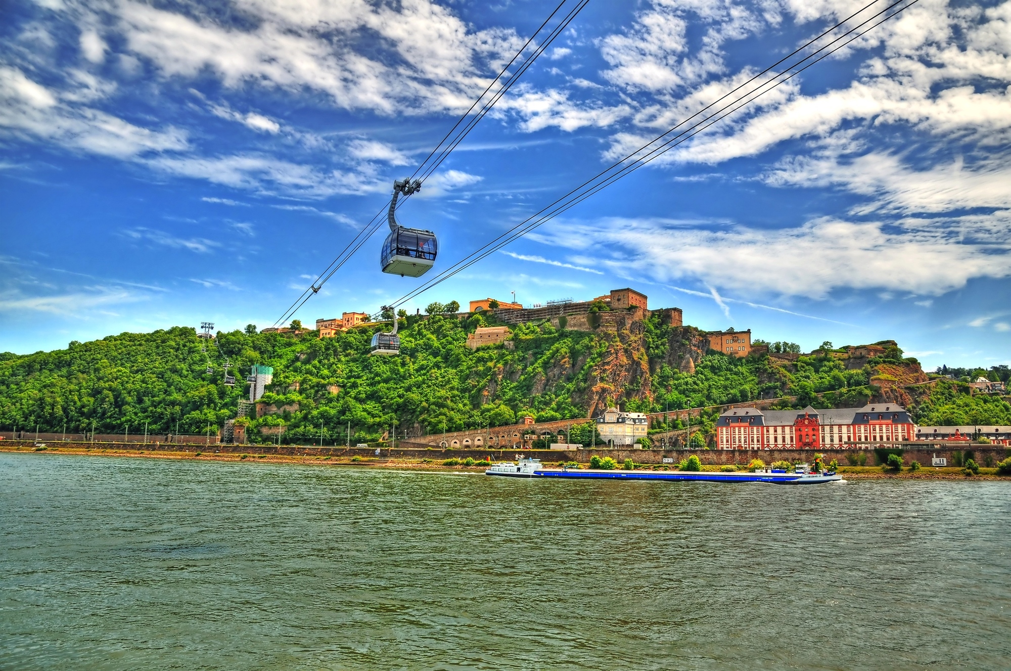 Beautiful HDR image of Fortress Ehrenbreitstein on the mountain in Koblenz over the Rhine river with cable cars moving through mountains.